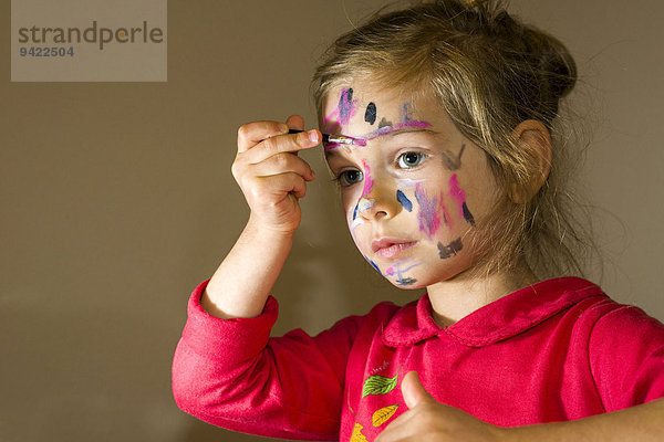 Mädchen bemalt sein Gesicht mit bunten Wasserfarben  Deutschland