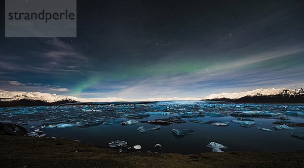 Eisbrocken im Wasser zur blauen Stunde mit Polarlicht  See Jökulsárlón  Vik  Island