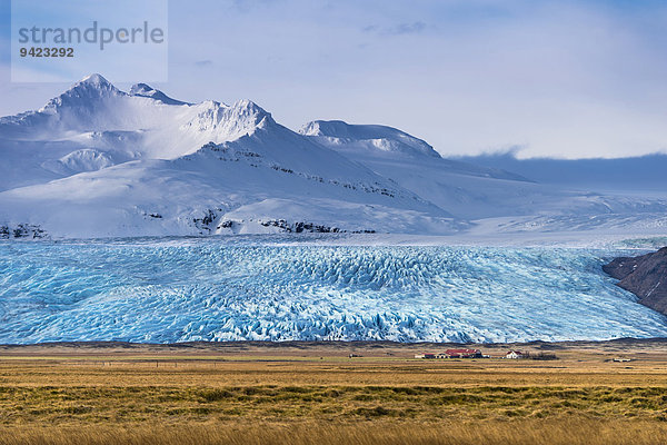 Isländisches Gehöft mit Gletscherzunge und verschneiten Bergen  Höfn  Island