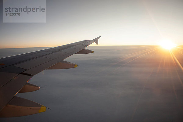 Sonnenaufgang vom Flugzeug über den Wolken mit Tragwerk  über Norwegen
