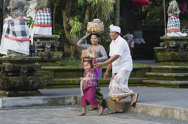 Eine balinesiche Familie kommt vom Tempelfest  Pura Dalem Puri Tempel  Peliatan  Ubud  Bali  Indonesien