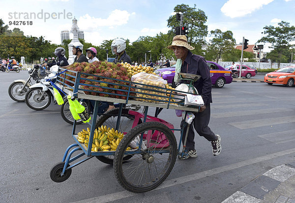 Gemüsehändler schiebt seine Karre im Straßenverkehr  Bangkok  Thailand