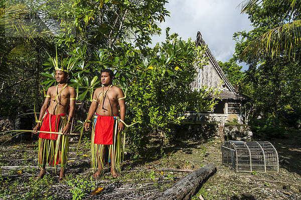 Zwei traditionell gekleidete Männer stehen vor Steingeld  Insel Yap  Westkarolinen  Mikronesien