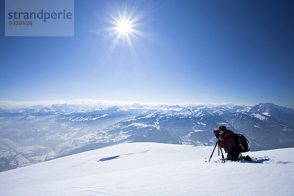 Fotograf beim Fotografieren mit Stativ in den verschneiten Alpen am Chäserrugg im Toggenburg  Schweiz  Europa