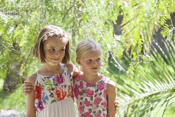 Verstecktes Porträt von zwei Mädchen  die im Garten wegschauen
