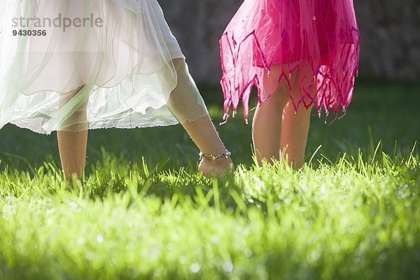 Ausschnitt aus den Beinen zweier Mädchen in Feenkostüm im Garten
