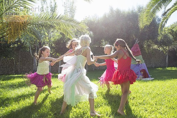 Fünf energische Mädchen in Feenkostüm spielen im Garten