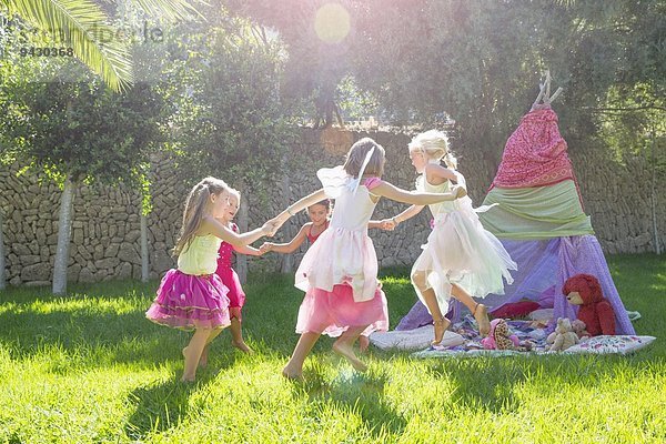 Fünf Mädchen in Feenkostüm spielen im Garten