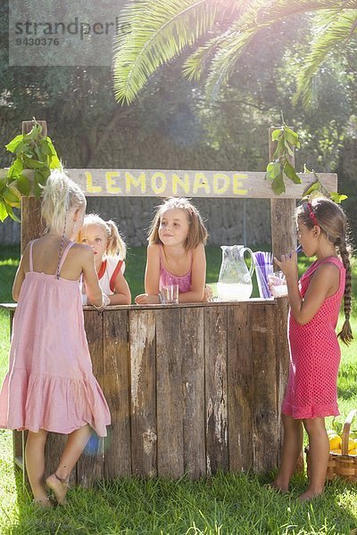 Vier Mädchen  die am Limonadenstand im Park kaufen und verkaufen.