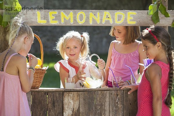 Verstecktes Porträt von vier Mädchen am Limonadenstand im Park