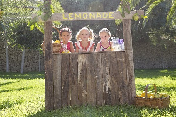 Porträt von drei Mädchen  die Limonade am Stand im Park verkaufen