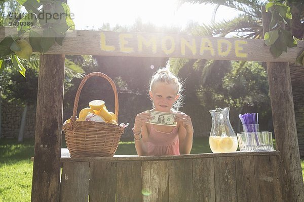 Porträt eines Mädchens auf einem Limonadenständer mit einem Dollarschein