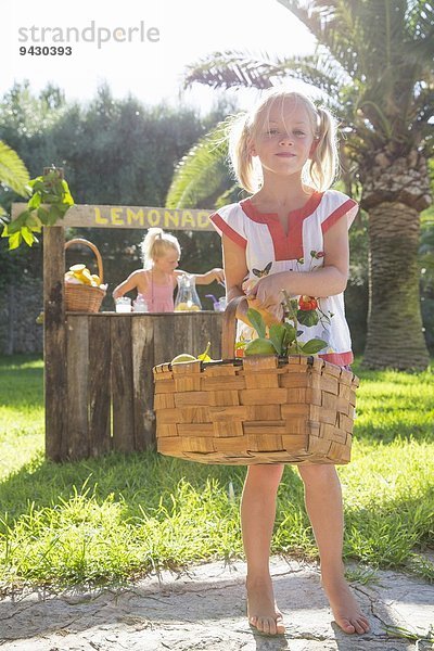 Porträt des Mädchens mit Zitronenkorb vor dem Limonadenständer