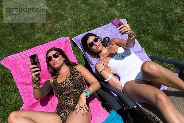 Zwei Schwestern beim Sonnenbaden auf Liegestühlen im Garten