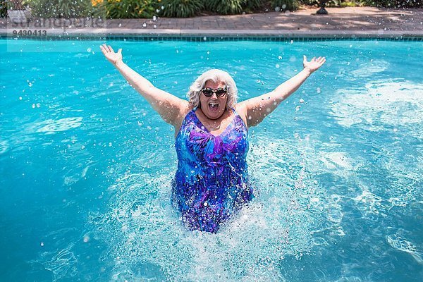 Porträt einer reifen Frau  die im Schwimmbad plätschert.