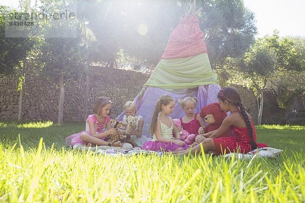 Fünf Mädchen spielen mit Teddybären vor dem Tipi