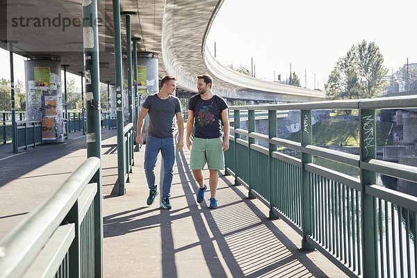 Zwei junge Männer  die über die Brücke gehen.