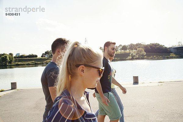 Vier junge Freunde  die am Flussufer spazieren gehen.