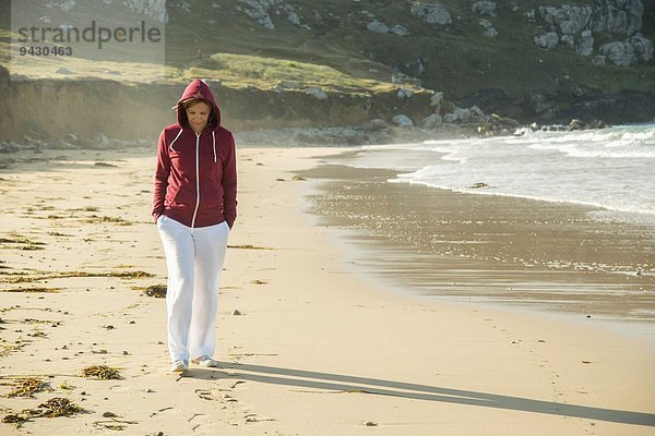 Reife Frau beim Strandspaziergang mit den Händen in den Taschen  Camaret-sur-mer  Bretagne  Frankreich