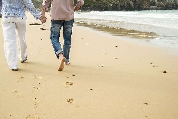 Ausschnitt eines reifen Paares  das beim Spaziergang am Strand Händchen hält  Camaret-sur-mer  Bretagne  Frankreich