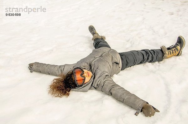 Mädchen auf dem Rücken im Schnee liegend