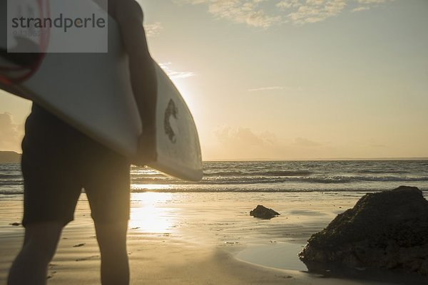 Erwachsener Mann  auf das Meer zugehen  Surfbrett haltend