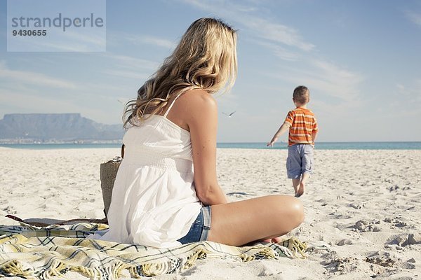Mittlere erwachsene Mutter  die den jungen Sohn beim Spielen am Strand beobachtet  Kapstadt  Westkap  Südafrika