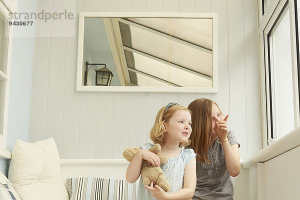 Zwei Schwestern  die aus dem Fenster der Ferienwohnung schauen.