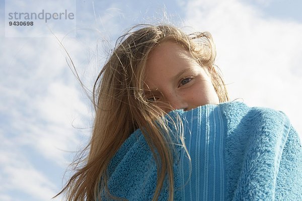 Portrait des Mädchens in Handtuch gewickelt an der luftigen Küste