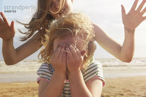 Mädchen mit Augen vor der Schwester am Strand  Camber Sands  Kent  UK