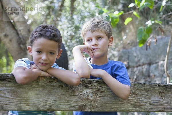 Porträt von zwei Jungen  die sich am Gartenzaun lehnen