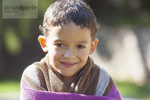 Porträt eines Jungen mit nassen Haaren in Handtuch gewickelt im Garten