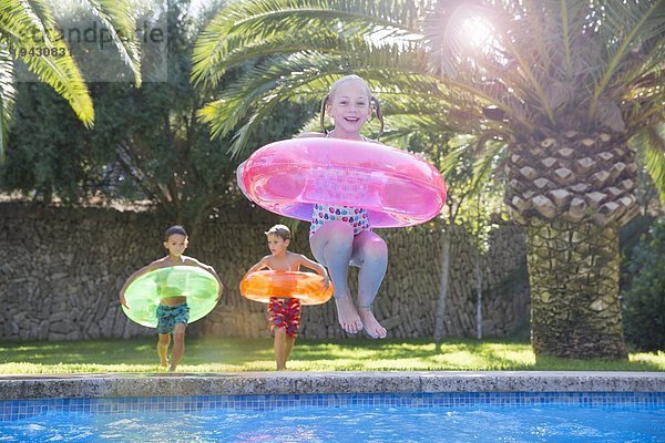 Mädchenspringen mit aufblasbarem Ring im Gartenschwimmbad