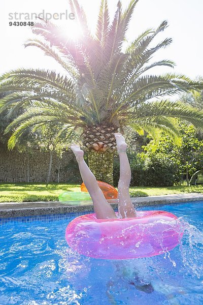 Mädchen taucht in einen aufblasbaren Ring im Gartenschwimmbad ein.