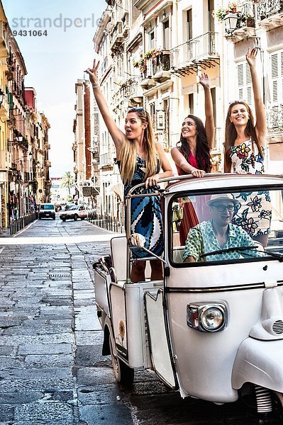 Drei junge Frauen winken vom offenen Rücksitz des italienischen Taxis  Cagliari  Sardinien  Italien