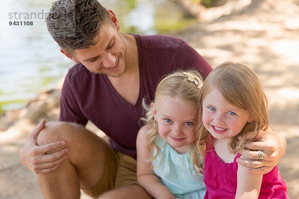 Porträt von Vater und zwei Töchtern am Flussufer