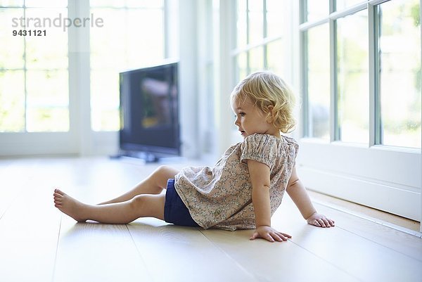Portrait weibliches Kleinkind auf dem Wohnzimmerboden sitzend