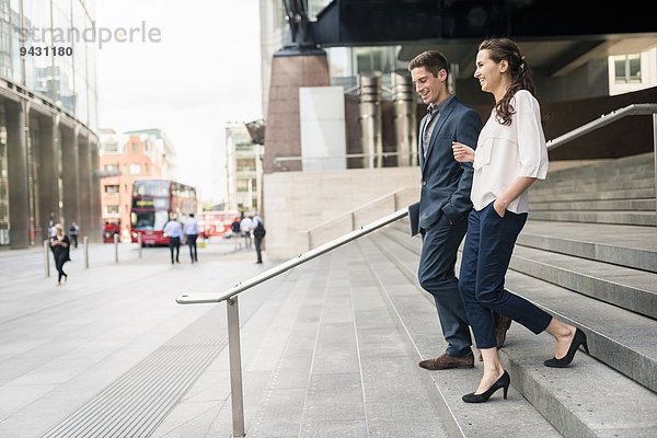 Rückansicht eines jungen Geschäftsmannes und einer jungen Frau  die sich beim Treppensteigen unterhalten  London  UK