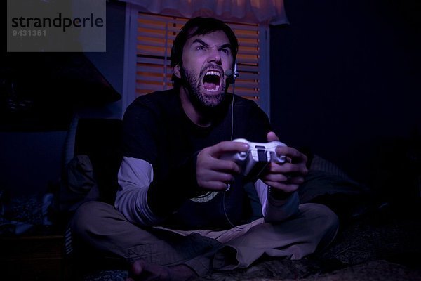 Mittlerer Erwachsener Mann schreit  während er nachts ein Videospiel spielt.