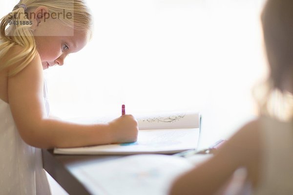 Zwei Schwestern beim Malen in Büchern mit Buntstiften