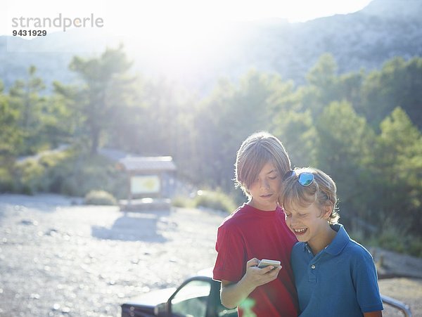 Zwei Brüder betrachten Text auf dem Smartphone  Mallorca  Spanien