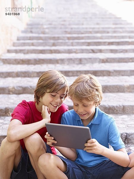 Brüder  die sich das digitale Tablett auf der Dorftreppe ansehen  Mallorca  Spanien