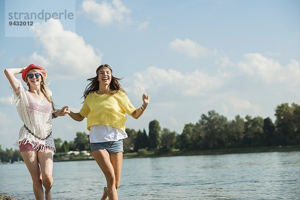 Zwei Freundinnen laufen am See entlang