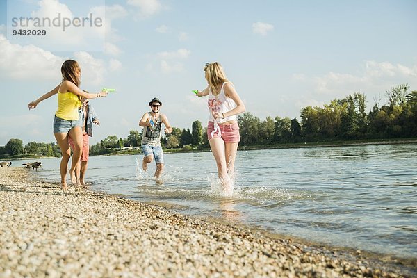 Freunde spielen mit Wasserpistolen im See