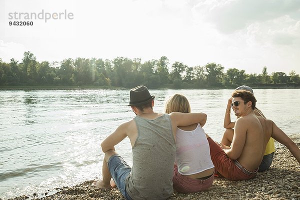 Vier junge Freunde sitzen am Seeufer