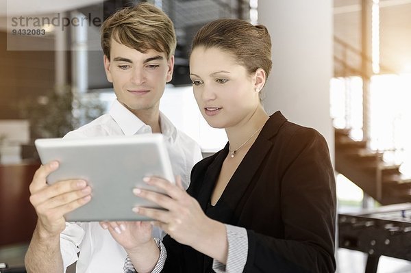 Geschäftsfrau und Geschäftsmann mit digitalem Tablett im Gespräch