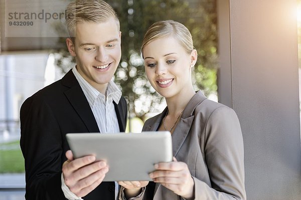 Geschäftsfrau und Geschäftsmann mit digitalem Tablett im Gespräch