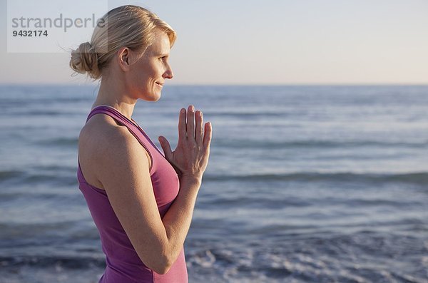 Frau im Yoga-Gebet Pose am Strand