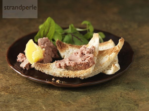 Weihnachtssnack aus Hühnerleberparfait mit Calvados. Grüne Salatblätter und geröstete Weißbrotbrösel