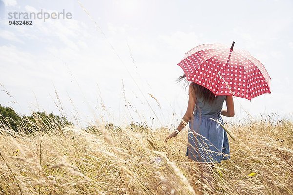 Junge Frau im Feld mit Regenschirm